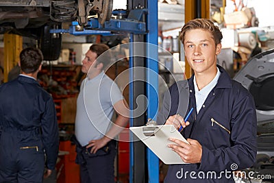 Portrait Of Apprentice Mechanic Holding Clipboard Working In Auto Repair Shop Stock Photo