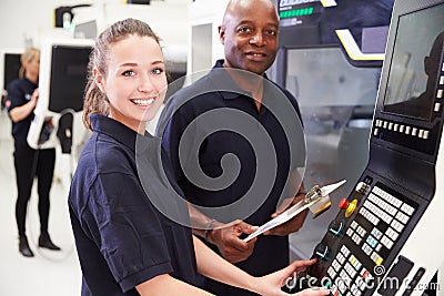 Portrait Of Apprentice Working With Engineer On CNC Machine Stock Photo