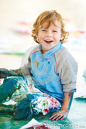 Portrait, art and a boy painting on the floor of a studio for creative expression or education at school. Smile, paint Stock Photo