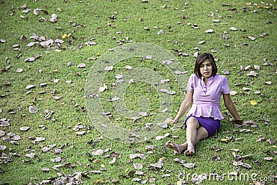 Portrait Asean woman sitting on the lawn in a park Stock Photo