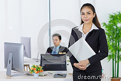 Portrait asian adult woman office people wearing suit standing and holding laptop looking at camera look to confident. Backward Stock Photo