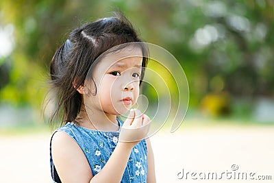 Portrait Asian child girl eating snack at outdoors. Kid hungry after playing in public park. Children is feeling hot and sweating Stock Photo