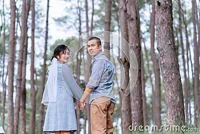 Portrait of an Asian couple posing for a pre-wedding photo in identical blue outfits, happily showing off their expressions of Stock Photo