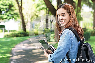 Portrait of asian female colleges student holding textbook in her hands and standing outdoors at university campus Stock Photo