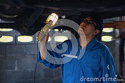 Portrait of asian male car mechanic performing car checking and maintenace service at garage and car maintenance service station Stock Photo