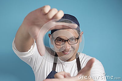 Portrait of Asian male chef or waiter looking at camera and smiling while framing his face with hands Stock Photo