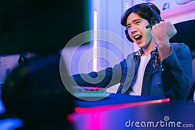 Portrait of Asian male gamer celebrating victory in front of the gaming table. Gamer winning an esports game with victory emotion Stock Photo