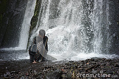 A traveler relaxing and bathing under a swift waterfall Stock Photo