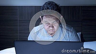 Tired Sleepy Man Working on Laptop untill Midnight on Bed Stock Photo