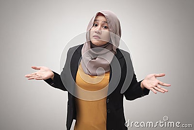 Portrait of Asian muslim businesswoman wearing hijab shows refusal or denial gesture, shoulder shrug Stock Photo