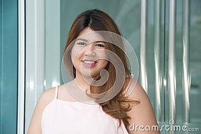 Portrait of Asian pretty smiley face fat woman posing front of building. Stock Photo