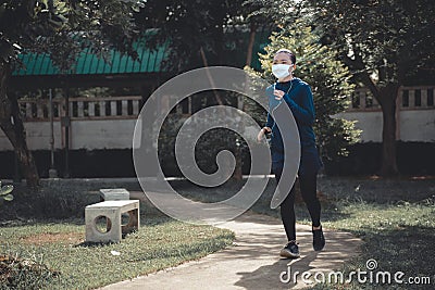 Portrait of Asian woman running at village park listening to music and wearing mask Stock Photo