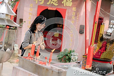 Portrait of asian woman saying prayers and eyes close in front of local Chinese shrine in Bangkok, Thailand Stock Photo