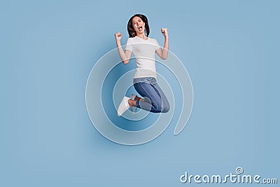 Portrait of astonished cheerful champion lady jump raise fists open mouth on blue background Stock Photo