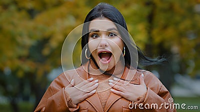 Portrait astonished hispanic happy girl receives unexpected surprise in park outdoors young enthusiastic woman opens Stock Photo