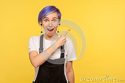 Portrait of astonished surprised fashionable hipster girl pointing to the side freespace for advertising. studio shot Stock Photo