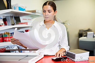 Portrait of an attentive woman checking quality of printing in printing house Stock Photo