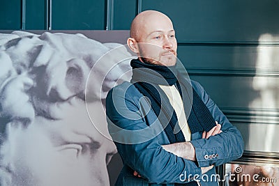 Portrait of attractive adult successful bald man art critic historian with beard in scarf in art gallery Stock Photo