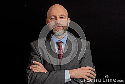 Portrait of a attractive bald businessmen in grey suit on black background. The model is in his 40s, shaven head and grey and dark Stock Photo