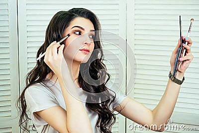 Portrait of attractive and beautiful woman make-up artist visagiste beauty blogger sitting in front of a mirror and Stock Photo