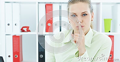 Portrait of an attractive business woman with finger on lips. Young businesswoman in office asking for silence. Stock Photo