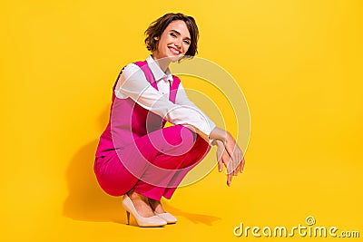 Portrait of attractive cheerful chic classy girl sitting posing good mood isolated over bright yellow color background Stock Photo