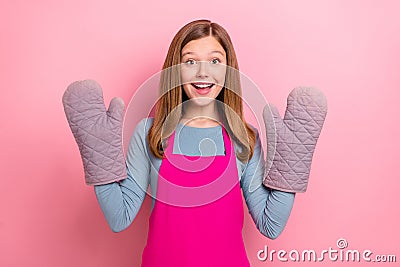 Portrait of attractive cheerful funny girl wearing apron gloves domestic culinary isolated over pink pastel color Stock Photo