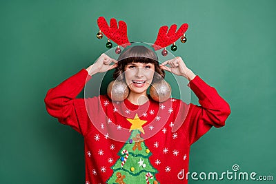 Portrait of attractive cheerful girl wearing festal look tree balls like earrings isolated over green color background Stock Photo