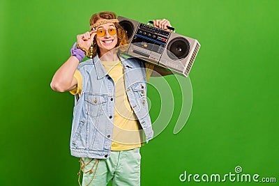 Portrait of attractive cheerful guy hippie holding tape player good mood rest isolated over bright green color Stock Photo