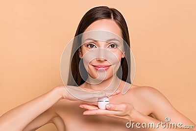 Portrait of attractive cheerful naked woman holding in hand vitamin cream collagen isolated over beige pastel color Stock Photo