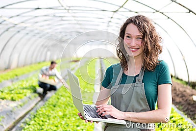 Portrait of an attractive farmer in a greenhouse using laptop Stock Photo