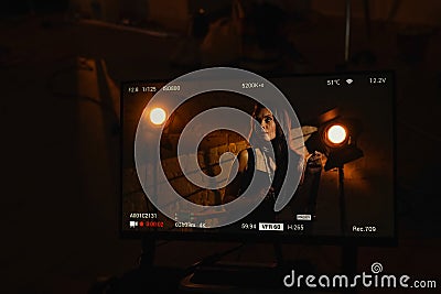 Portrait of attractive female actress. Shot of monitor with brunette woman in black dress with hairstyle and pearls Stock Photo