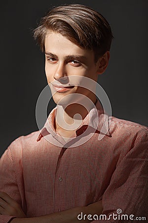 Portrait of attractive kind young man with folded and crossing hands standing Isolated on black background and looking Stock Photo
