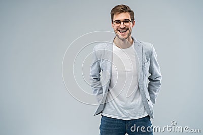 Portrait of attractive masculine fashionable modern stylish guy wearing blue blazer, jeans keeping hands in pockets Stock Photo