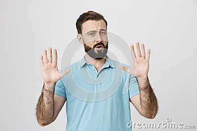 Portrait of attractive mature man showing hold on gesture with raised palms and opened mouth, standing over gray Stock Photo