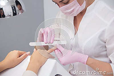 A manicurist gives a manicure to a client. Portrait of an attractive nail salon worker giving a manicure to one of her Stock Photo