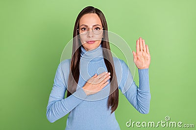 Portrait of attractive serious content long-haired girl promising loyalty isolated over bright green color background Stock Photo