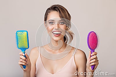 Portrait of attractive smiling woman holding hairbrushes Stock Photo