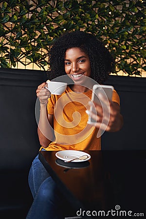 An attractive smiling young woman taking selfie on mobile phone in cafe Stock Photo