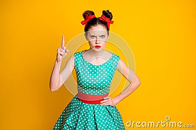 Portrait of attractive strict serious girl wearing dotted teal dress threatening forefinger isolated over vivid yellow Stock Photo