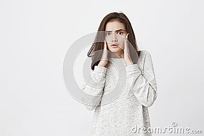 Portrait of attractive tender girl, stunned and shocked of what she sees, holding hands on face with half-opened mouth Stock Photo