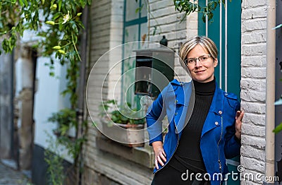 Portrait of an attractive thirty year old white woman posing at a traditional white and green facade Stock Photo