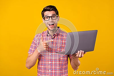 Portrait of attractive trendy cheerful guy geek using demonstrating laptop sign over bright yellow color Stock Photo