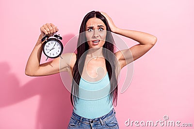 Portrait of attractive worried funky long-haired girl holding clock oops over pink pastel color background Stock Photo