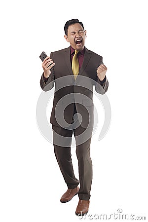 Attractive young businessman receive bad news on his phone, angry screaming gesture Stock Photo