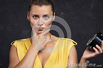 Portrait of attractive young woman with clock. An unsatisfied woman is holding a watch. Watch Time concept. Time is over. Stock Photo