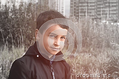 Portrait of baby boy in dark jacket on high colorless grass background Stock Photo