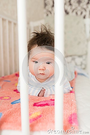 Portrait of a baby in the crib. High angle portrait of a beautiful baby with a finger in his mouth, lying on the bed, his eyes Stock Photo
