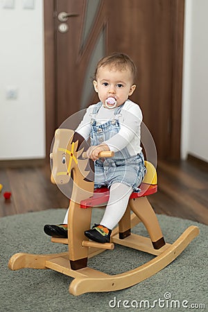 Portrait of baby girl playing on wooden rocking horse. Childhood, game at home concept Stock Photo