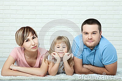 Portrait of baby and her parents lying on carpet in living room Stock Photo
